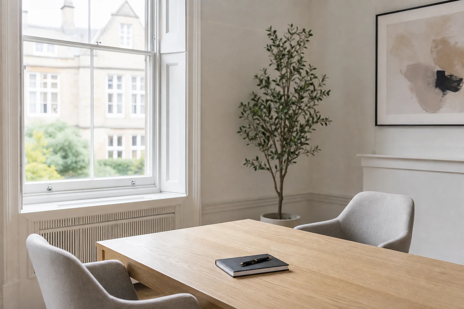 A calm modern meeting room with a pale oak table and sash window, ready for a legal consultation